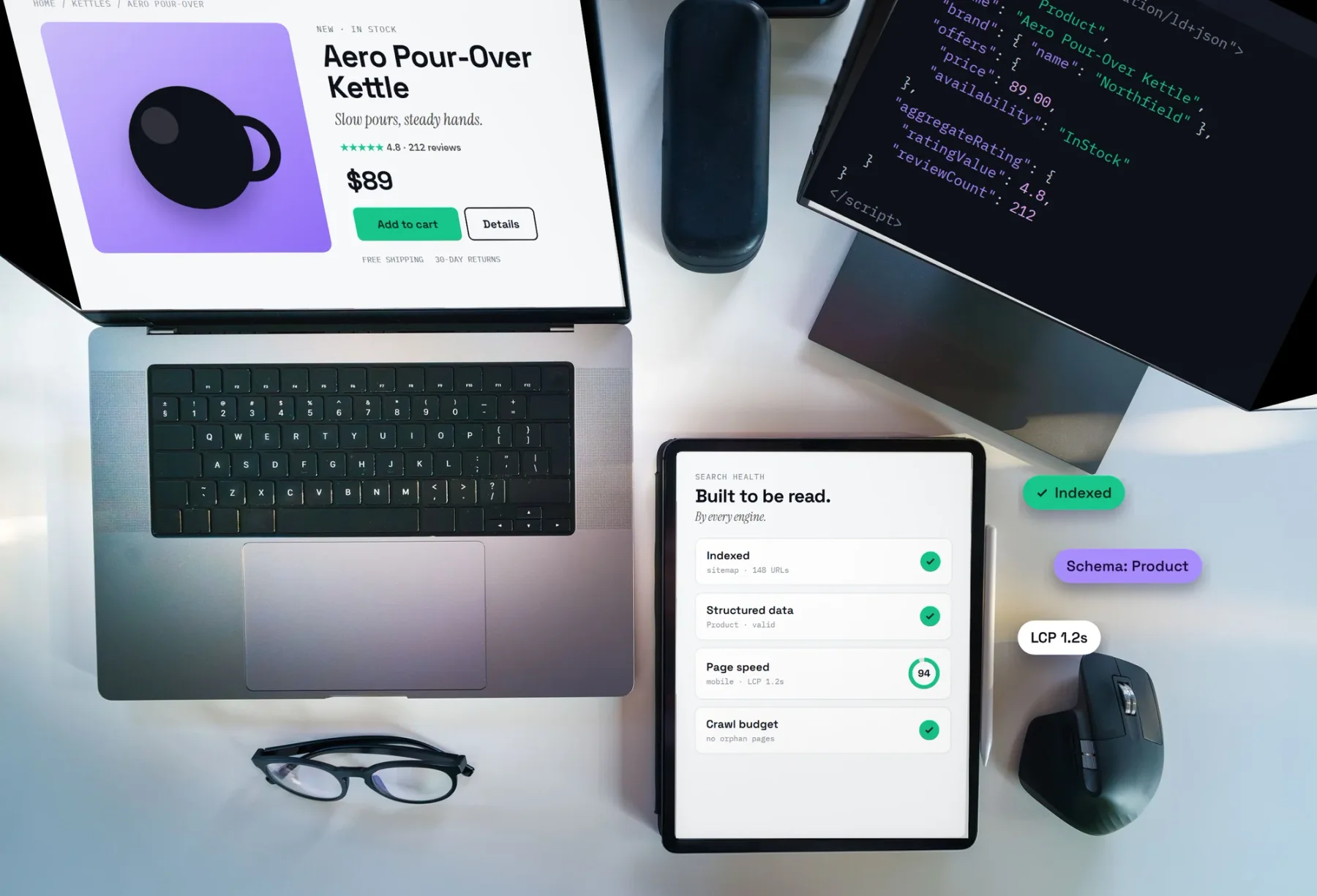 A desk with a product page on a laptop, its structured data in a code editor, and a search health checklist on a tablet: indexed, structured data valid, page speed 94